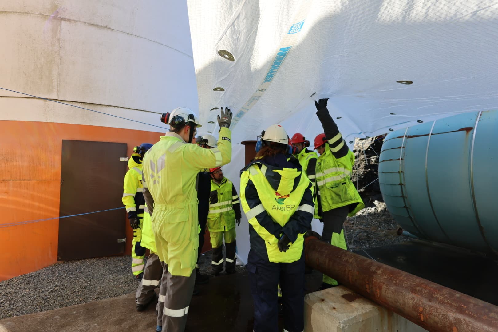 Workers inspecting pipes at an energy facility